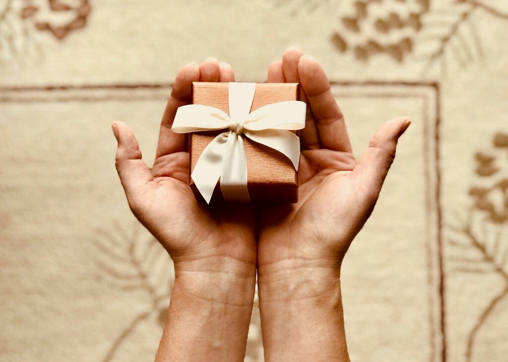 Close-up of hands holding a beautifully wrapped gift box with a ribbon, perfect for celebrations and surprises.